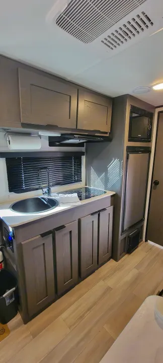 RV rental kitchen: modern design with sink, cooktop, microwave, fridge, and ample storage for travel comfort.. Heartland RVs Mallard Pathfinder 2022