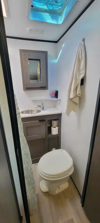 Compact RV rental bathroom with a modern design, featuring a sink, toilet, mirrored cabinet, and overhead vent.. Heartland RVs Mallard Pathfinder 2022