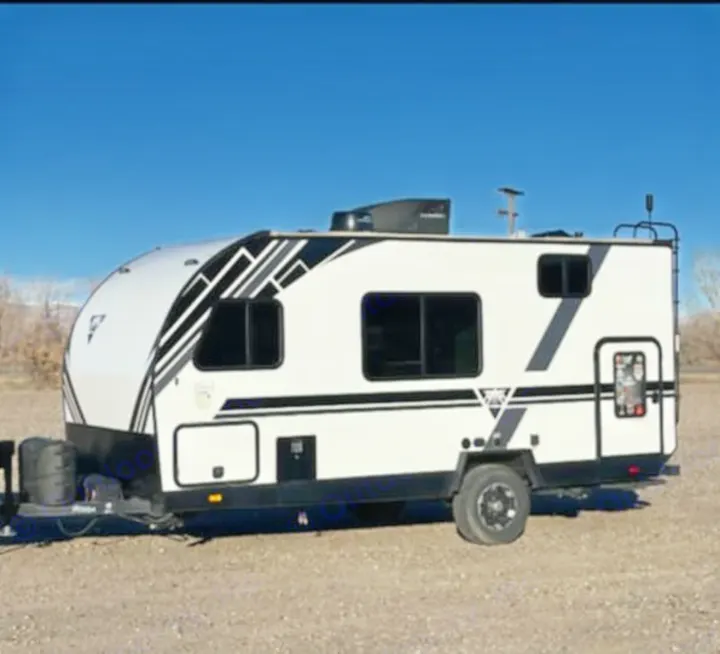 A sleek white and black travel trailer, parked on gravel under a blue sky. Available for RV rental and camping trips.. Heartland RVs Mallard Pathfinder 2022