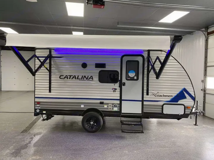 A Coachmen Catalina travel trailer, ideal for RV rental, with an extended awning and bright blue LED lights.. Coachmen 164BHX 2023