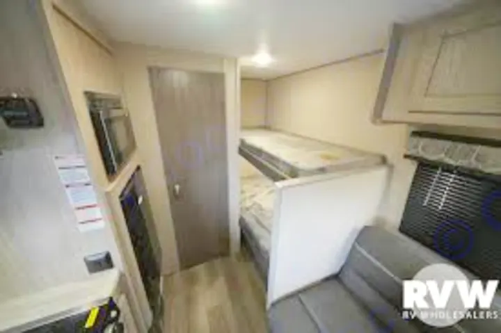 Compact RV rental interior: bunk beds, sofa, & kitchen appliances, ideal for family travel.. Coachmen 164BHX 2023