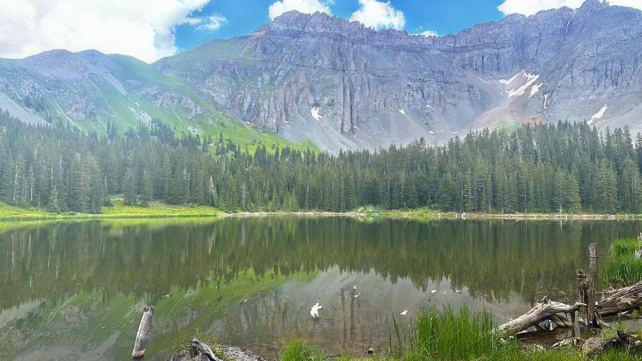 Tranquil mountain lake reflects pine forests & rugged peaks. Ideal scenic spot for an RV rental vacation, exploring nature's beauty.. Entegra Coach Qwest 2020