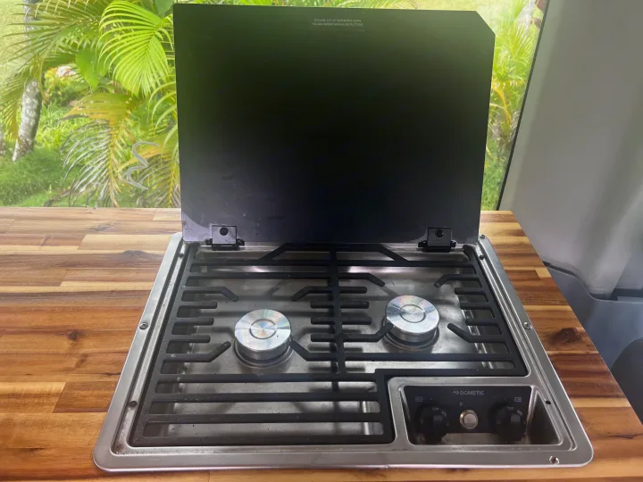 This RV rental features a Dometic two-burner camper stove with a raised cover, ideal for cooking on the go.. Ford Transit Custom 2016