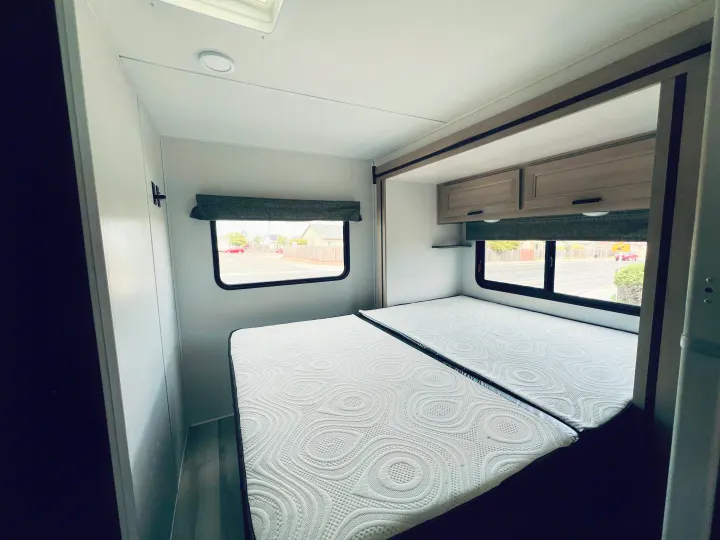 Spacious RV rental bedroom with two comfortable mattresses, overhead cabinets, and windows offering street views.. FOREST RIVER FORESTER 2251 SLE 2025