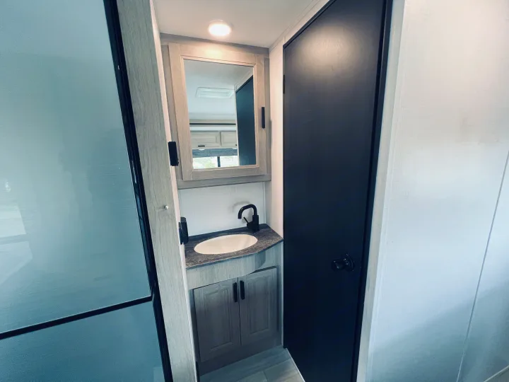 Compact RV rental bathroom with a modern vanity, sink, mirror, dark-framed shower, and black door.. FOREST RIVER FORESTER 2251 SLE 2025