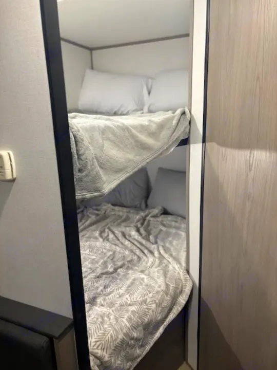 Neat, stacked bunk beds inside an RV rental. Both bunks are made with blankets and pillows, ready for your trip.. Coleman Lantern 2024