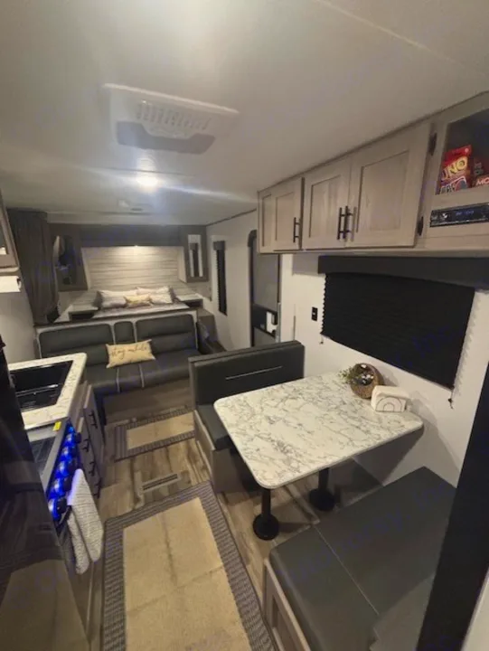 This RV rental interior features a modern kitchen, comfortable living area with a sofa, dinette, and rear bedroom.. Coleman Lantern 2024
