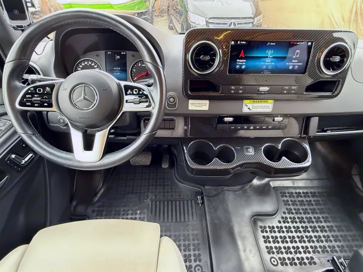 Interior of a Mercedes-Benz rv rental, featuring the dashboard, steering wheel, digital screen, and carbon fiber details.. Winnebago Era 2020