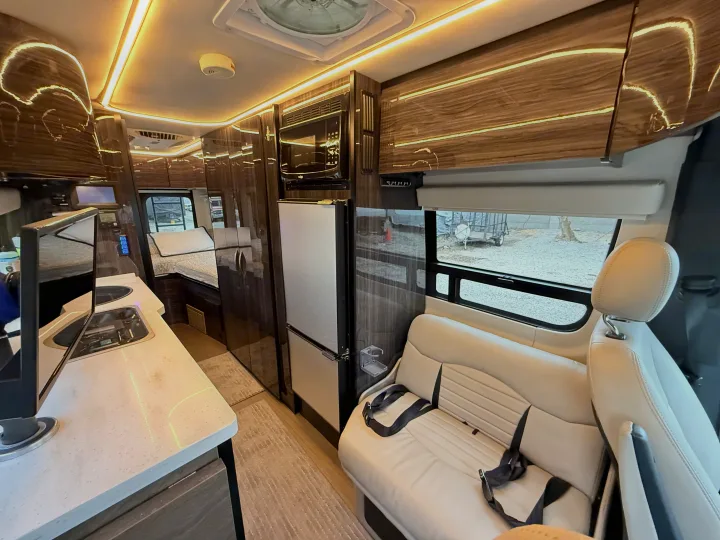 Spacious rv rental interior featuring a modern kitchen, comfortable seating area with a bench seat, and a rear bed.. Winnebago Era 2020