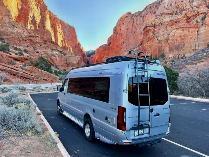 Experience epic views! A silver rv rental is parked amidst towering red rock canyon walls, ready for your next adventure.. Winnebago Era 2020
