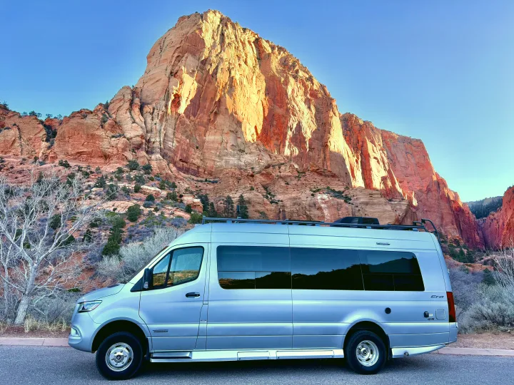 A silver Winnebago Era RV rental is parked on a road, with majestic red rock mountains under a clear blue sky.. Winnebago Era 2020