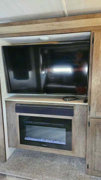Enjoy a modern RV rental with a built-in entertainment system featuring a TV, soundbar, and electric fireplace.. Forest River Wildwood 2021