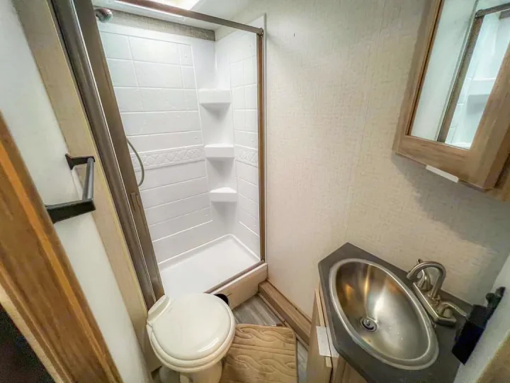 RV rental bathroom interior: compact shower, toilet, sink, and mirror cabinet, perfect for your travel needs.. Winnebago Minnie Winnie 2021