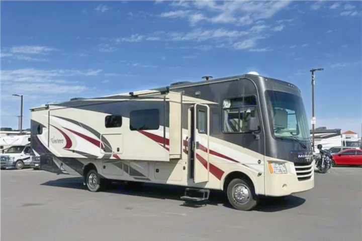 Modern Class A motorhome RV rental, beige and black with red accents, parked with slide-outs extended under blue sky.. Coachmen Mirada 2019
