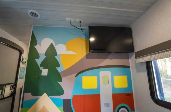 Fun RV rental interior with playful mural, TV, and ceiling vent. Perfect for family camping trips!. Forest River Salem 2022