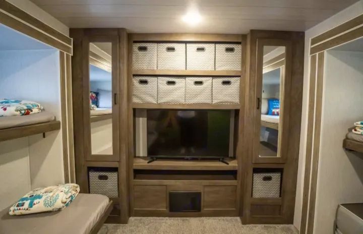 This RV rental interior features smart bunk beds, ample storage with bins, and a central entertainment unit with a TV.. Forest River Salem 2022