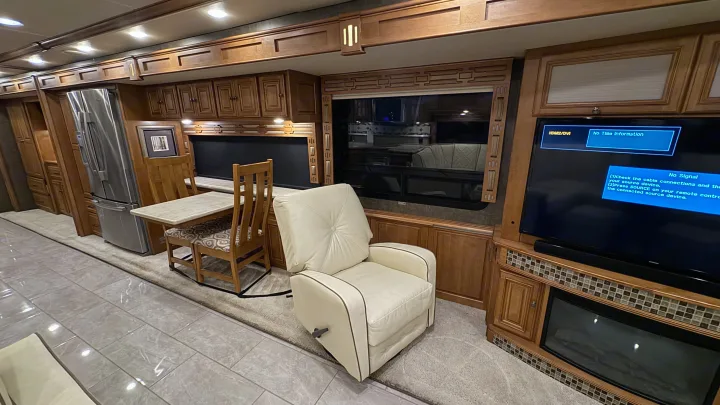 Spacious, modern RV rental interior with kitchen, dining area, cozy recliner, large TV, and fireplace.. Winnebago Ellipse 2016