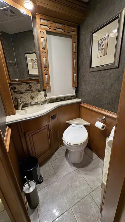 Clean RV rental bathroom with sink, toilet, and mirror, ready for your travels. Compact and functional design.. Winnebago Ellipse 2016