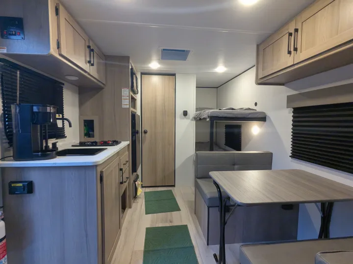 Spacious RV rental interior featuring a modern kitchen, bunk beds, and dining area, perfect for family adventures.. Keystone Coleman 2025