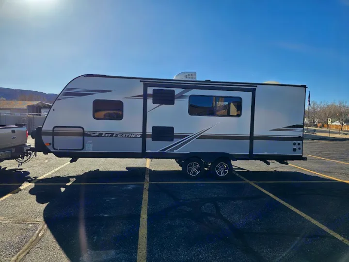 Modern Jay Feather travel trailer RV rental, towed by a pickup in a sunny lot. Great for travel.. Jayco Jay Feather 2021