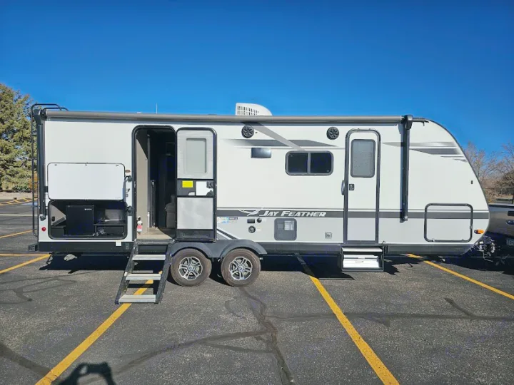 This Jay Feather RV rental, a light gray travel trailer, shows open doors & storage, ready for your next outdoor adventure.. Jayco Jay Feather 2021