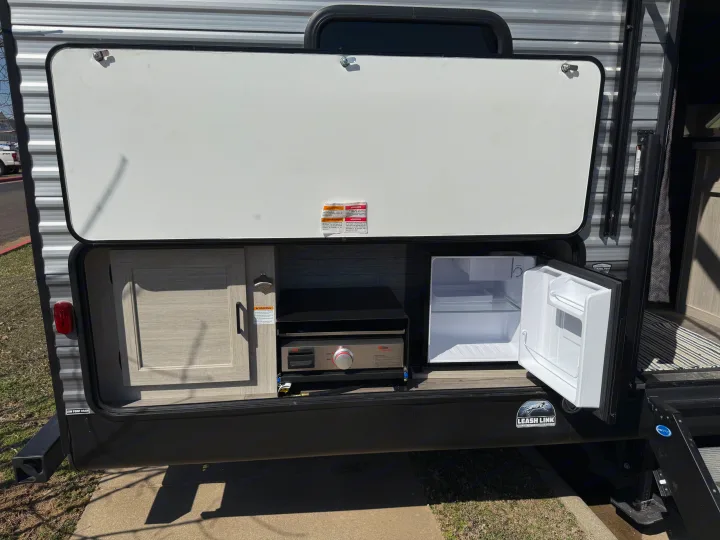 RV rental: Outdoor kitchen with flat-top griddle, open mini-fridge, and cabinet. Ready for your next camping adventure!. Coachmen Catalina 2024