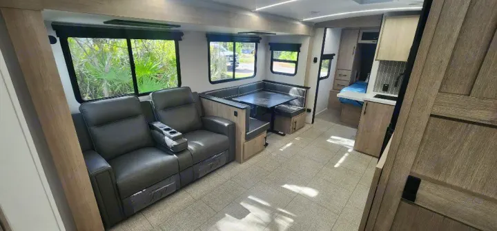 Spacious RV rental interior featuring comfortable recliners, dining booth, kitchen, and bedroom setup for travel.. Grand Design Imagine 2800BH 2025