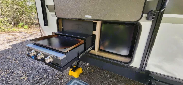 This RV rental features a convenient outdoor kitchen with a griddle and mini-fridge, perfect for campsite cooking.. Grand Design Imagine 2800BH 2025