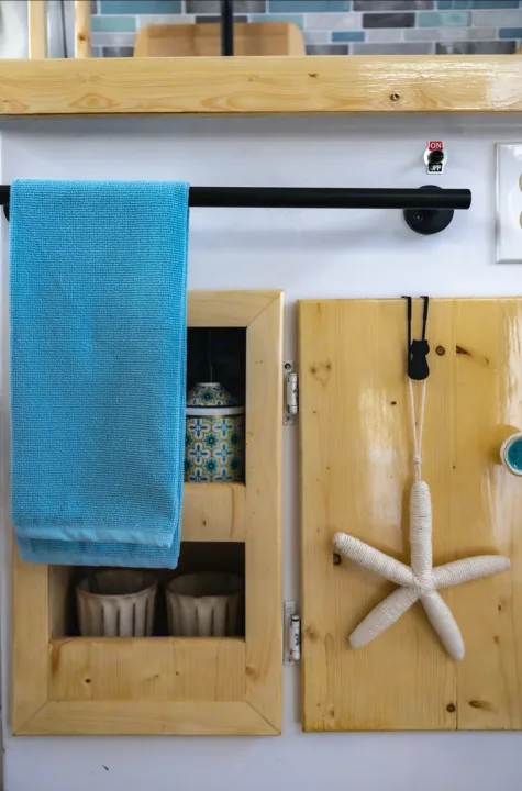 Cozy RV rental kitchen: blue towel, custom wood storage with jars/cups, and charming starfish decor.. Boler Boler 1974