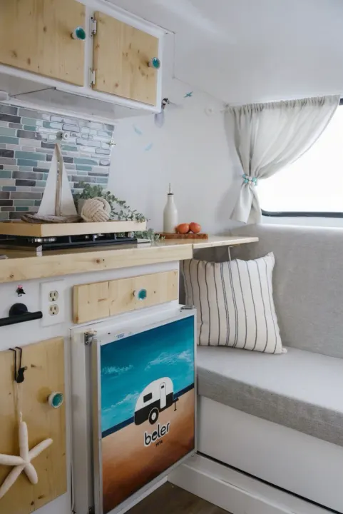 Cozy RV rental interior featuring a nautical kitchenette, beach decor, and comfy bench seating for your next trip.. Boler Boler 1974