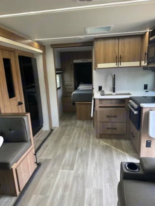 Bright rv rental interior featuring a modern kitchen, dinette, and a clear view into the rear sleeping area.. Grand Design Imagine 2024