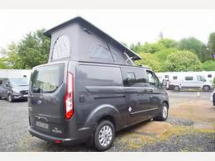 This dark grey Ford Transit pop-top campervan is perfect for RV rental. Rear view, roof raised, ready for trips.. Ford Triton 2024