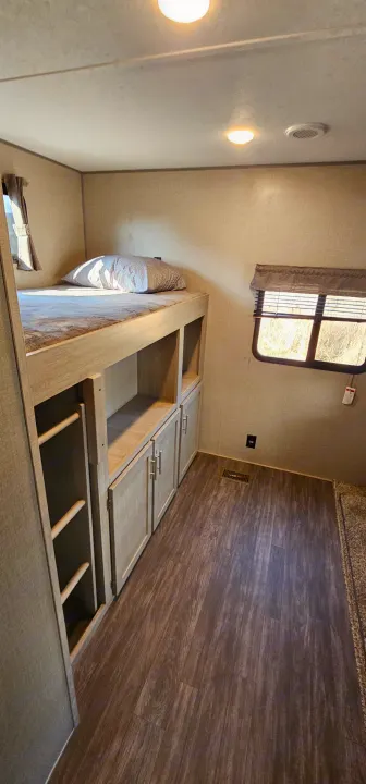 This RV rental features cozy bunk beds, storage, and modern wood-look floors, perfect for travel comfort.. Forest River Aurora 2022