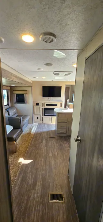 Interior of an RV rental: a modern living space featuring a sofa, dining area, kitchen, TV, and a cozy fireplace.. Forest River Aurora 2022