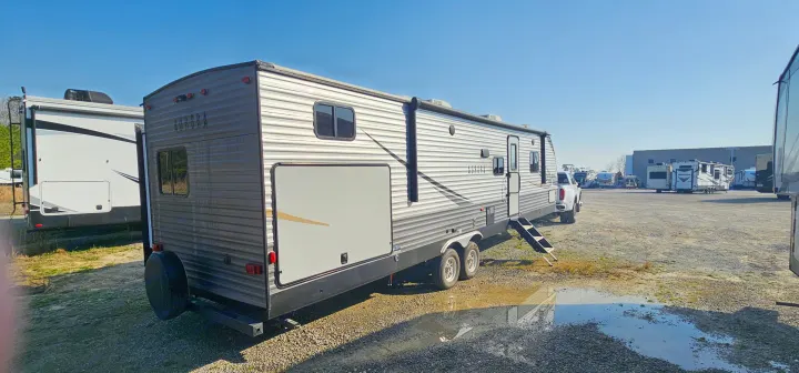 A grey Aurora travel trailer RV is on a gravel lot with a truck, steps extended. Other RVs are in the distance, great for rv rental.. Forest River Aurora 2022