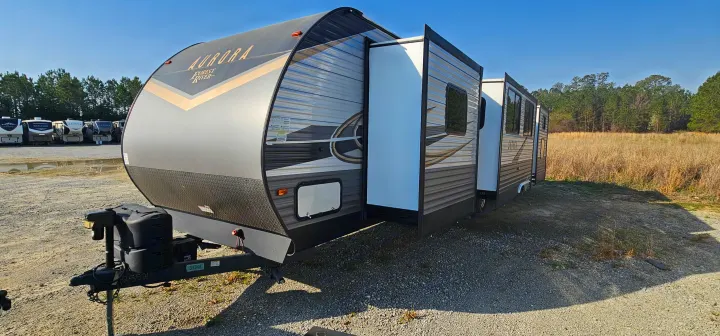 Modern grey & black Aurora Forest River travel trailer RV rental with slide-outs extended on a sunny gravel lot.. Forest River Aurora 2022