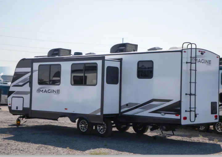 Explore the outdoors with this Imagine travel trailer rv rental, featuring a spacious slide-out, parked on a sunny gravel lot.. Grand Design Imagine 2800bh 2025