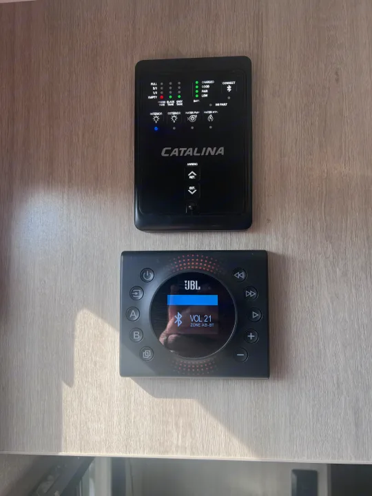 RV rental interior: Catalina control panel (tanks, battery, awning) & JBL audio system (VOL 21, Bluetooth).. Coachmen 164BHX 2023