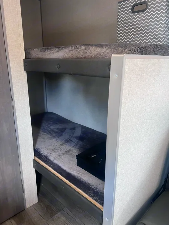 Inside this RV rental: comfortable bunk beds with cozy gray bedding, ideal for family camping trips.. Coachmen 164BHX 2023