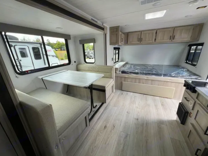Explore this modern RV rental interior featuring a dinette, compact bed, and overhead cabinets for cozy adventures.. East to West Della Terra 181BH 2025