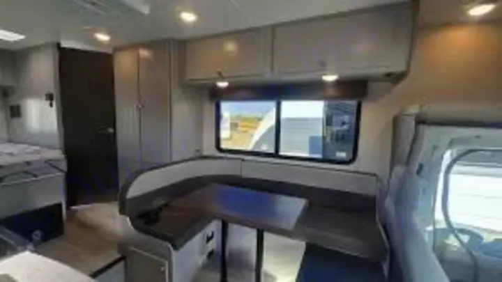 Inside this modern RV rental, find a comfortable U-shaped dinette with table, overhead storage, and bright windows.. Freelander 21QSS 2025
