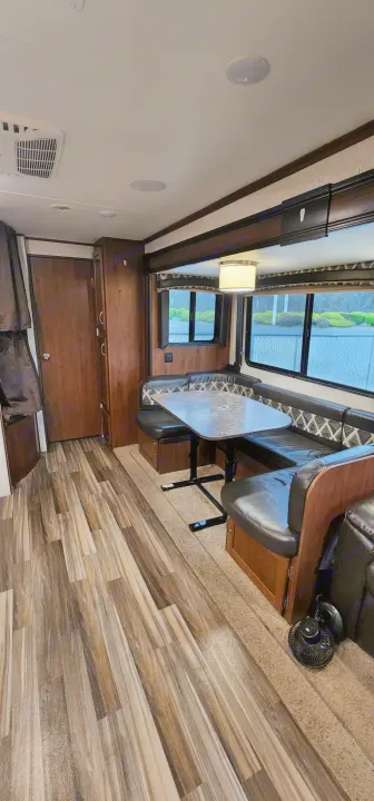RV rental interior showcasing a modern living space with a booth dinette, wood-look flooring, and large windows.. Jayco Jay Flight 2017