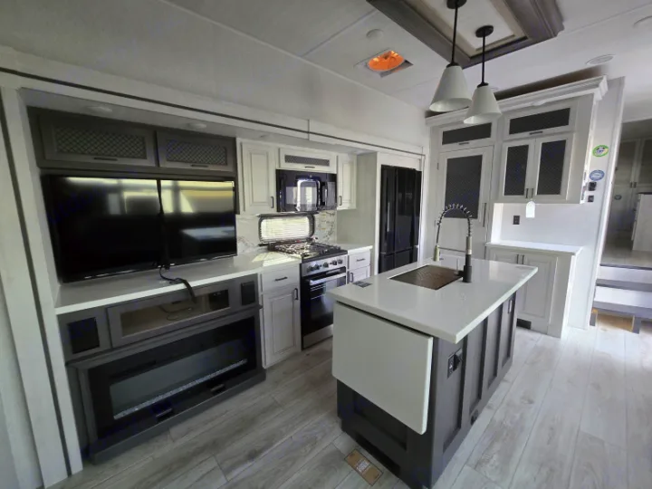 Spacious, modern RV rental interior featuring a full kitchen with island, living area with TV and fireplace. Perfect for your next adventure.. Forest River East to West Ahara 390DS 2025