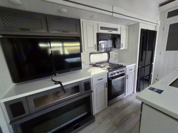 Modern RV rental interior with a cozy living area, TV, fireplace, and full kitchen.. Forest River East to West Ahara 390DS 2025