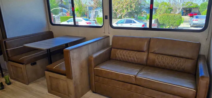 This RV rental interior features a comfortable dinette and sofa, creating a cozy and functional mobile living space.. Keystone Springdale 2025
