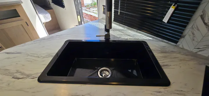 RV rental interior: black kitchen sink, modern faucet, and white marble-patterned countertop.. Keystone Springdale 2025