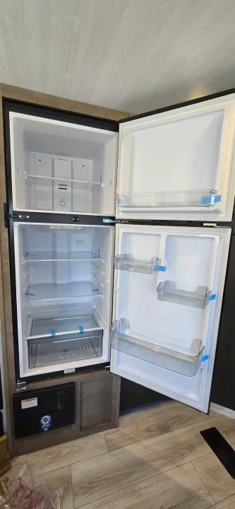 Inside a new, empty two-door refrigerator/freezer of an RV rental, awaiting your supplies for adventure.. Keystone Springdale 2025