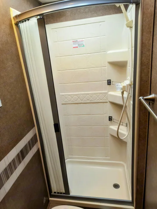 RV rental shower with a compact, molded interior, flexible door, and handheld showerhead. Efficient space design.. Thor Motor Coach Quantum 2020