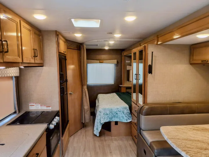 Spacious RV rental interior with a well-equipped kitchen, comfortable bedroom, and cozy dining booth. Perfect for travel.. Thor Motor Coach Quantum 2020