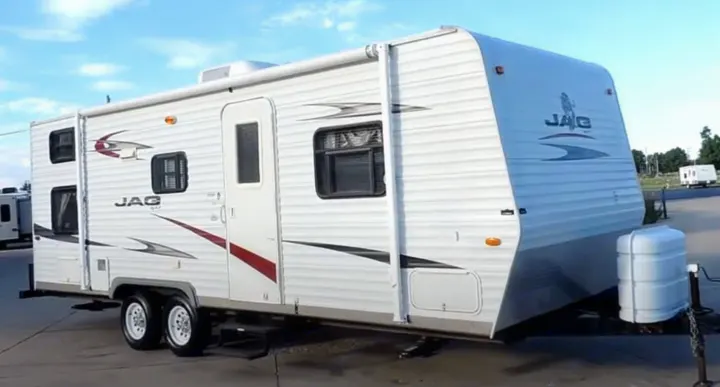 White Jag travel trailer, ideal for RV rental. Two-axle RV with awning & propane tanks, ready for adventures.. Jag Jag II 2007